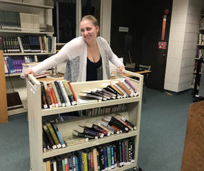 A female student is moving a cart full of books